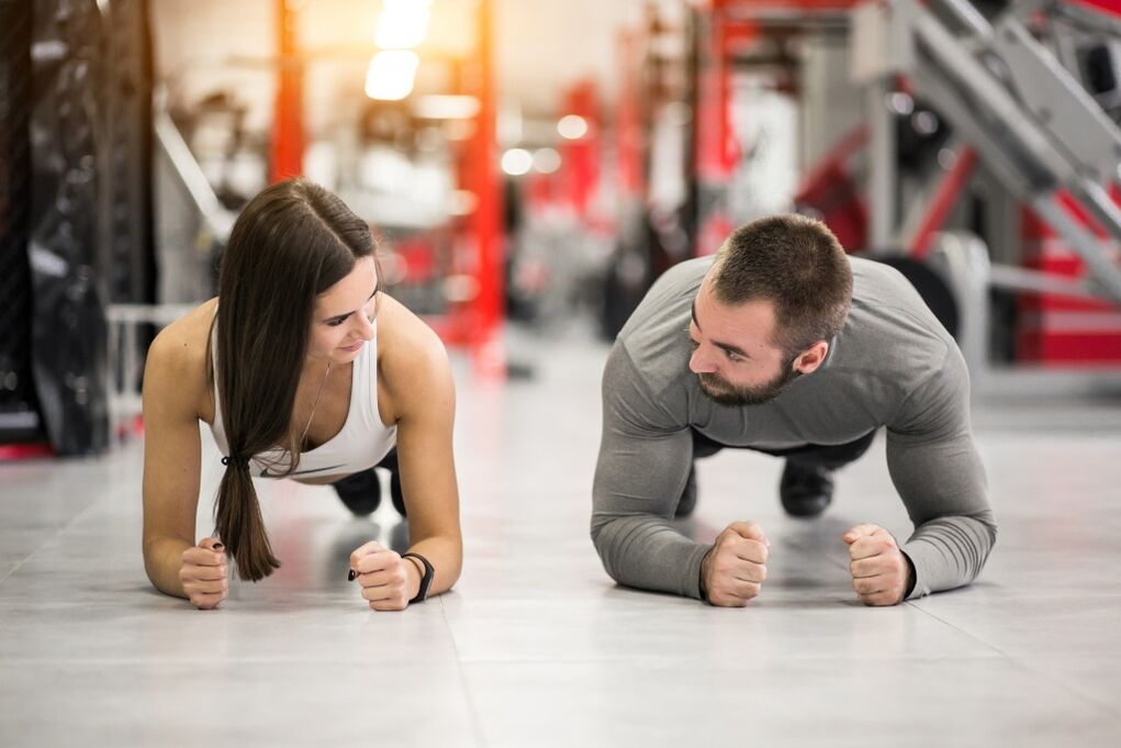 Un uomo e una donna eseguono l'esercizio della plancia progettato per tutti i gruppi muscolari